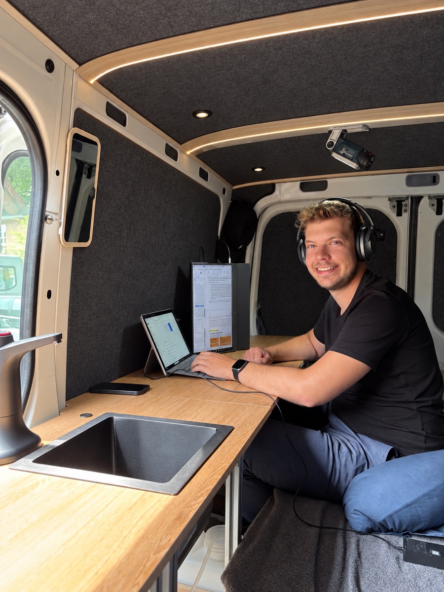 Markus Schulz arbeitet mit Kopfhörern am Büroplatz in seinem selbst ausgebauten Camper